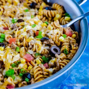 A blue bowl filled with pasta and vegetables,
