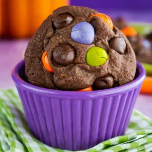 Chocolate Cookie with M&M candies in it, sitting in a purple bowl on top of a green and white napkin
