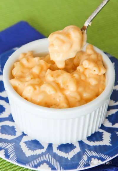 Macaroni and cheese in a white bowl with a spoonful being taken out