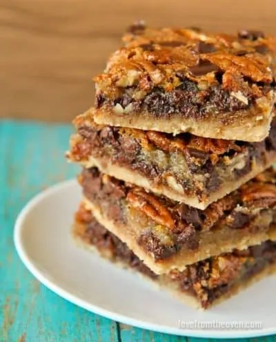 Four stacked pecan pie bars on a white plate