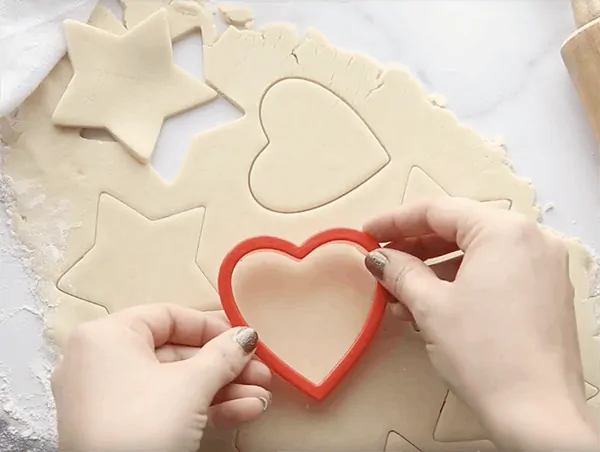 Shapes being cut out of sugar cookie dough
