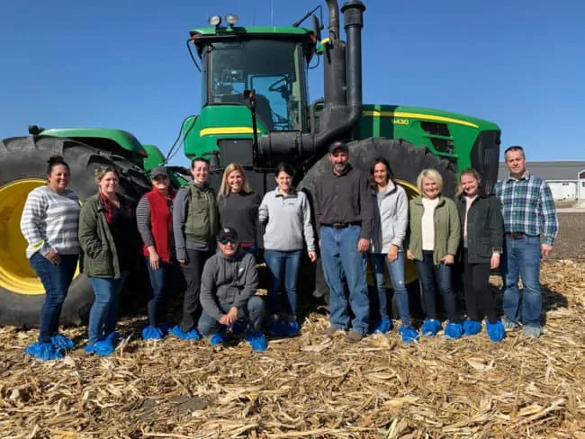 A group of people standing in front of a tractor posing for the camera