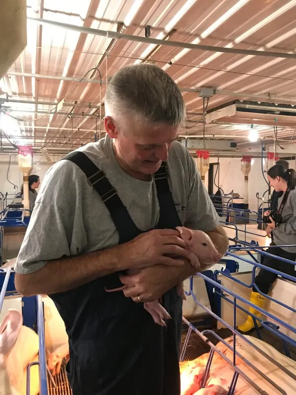 A man holding a baby pig