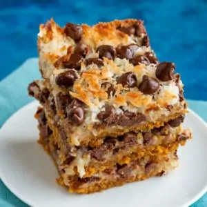 Three stacked magic cookie bars on a white plate
