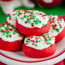 Several lofthouse style cookies with sprinkles on a red and white plate