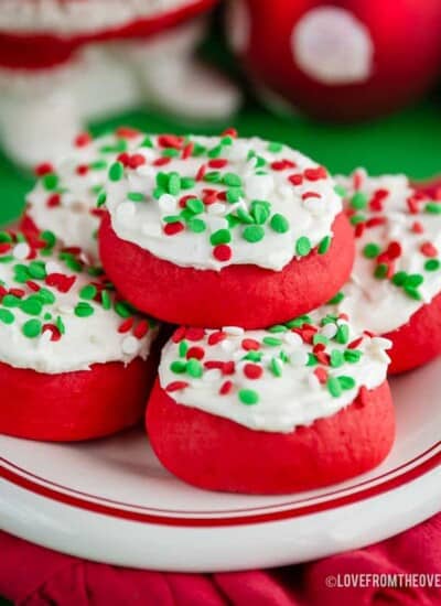 Several lofthouse style cookies with sprinkles on a red and white plate