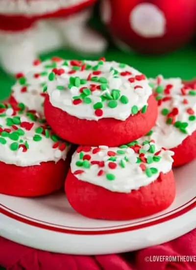 Several lofthouse style cookies with sprinkles on a red and white plate