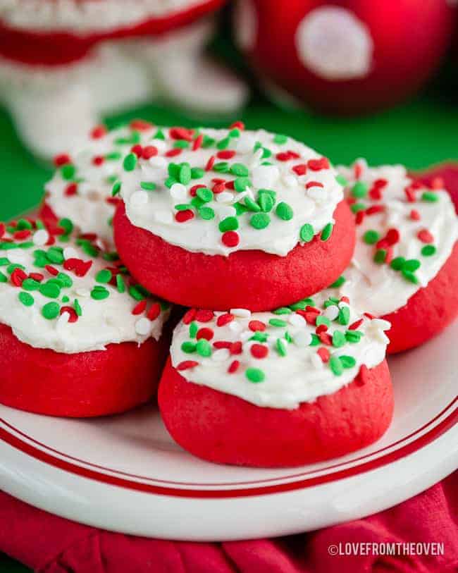 Several lofthouse style cookies with sprinkles on a red and white plate