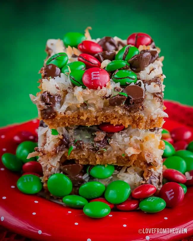 Three stacked magic cookie bars on a red plate