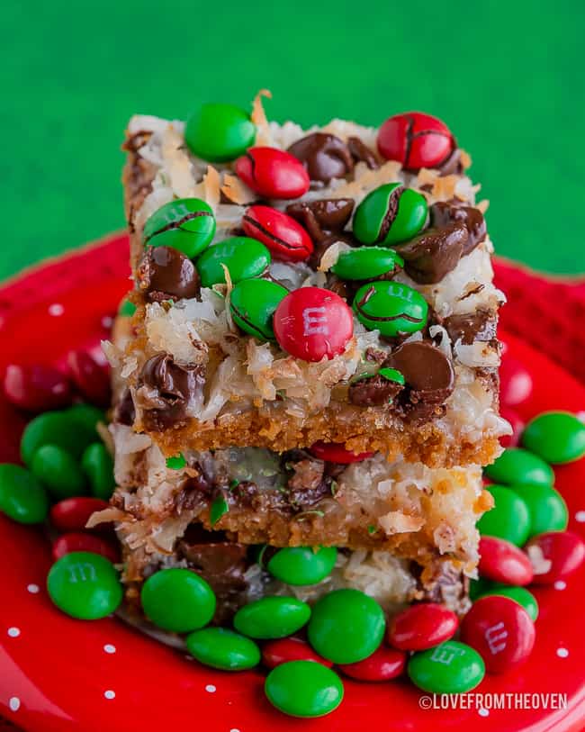 Stack of magic cookie bars covered in M&Ms on a red plate