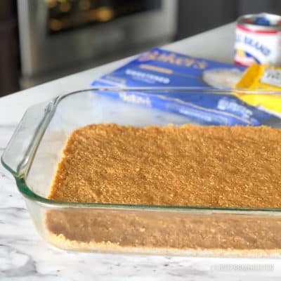 Crushed graham crackers packed into a glass baking pan