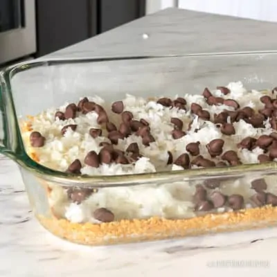 Uncooked magic cookie bars in a glass baking pan