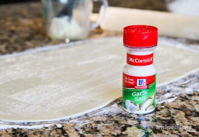 Rolled out dough next to a container of garlic salt