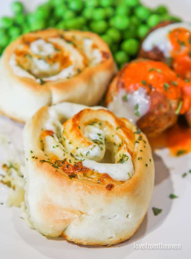 Garlic rolls on a plate with meatballs and peas