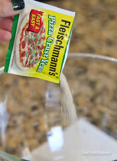 A packet of yeast being poured into a bowl