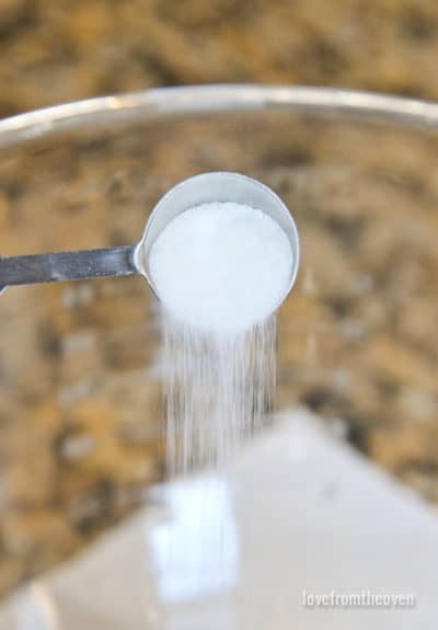 Salt being poured from a measuring spoon into a bowl