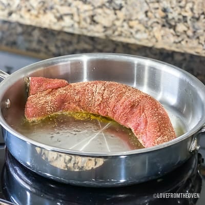 Raw pork tenderloin in a stainless steel pan