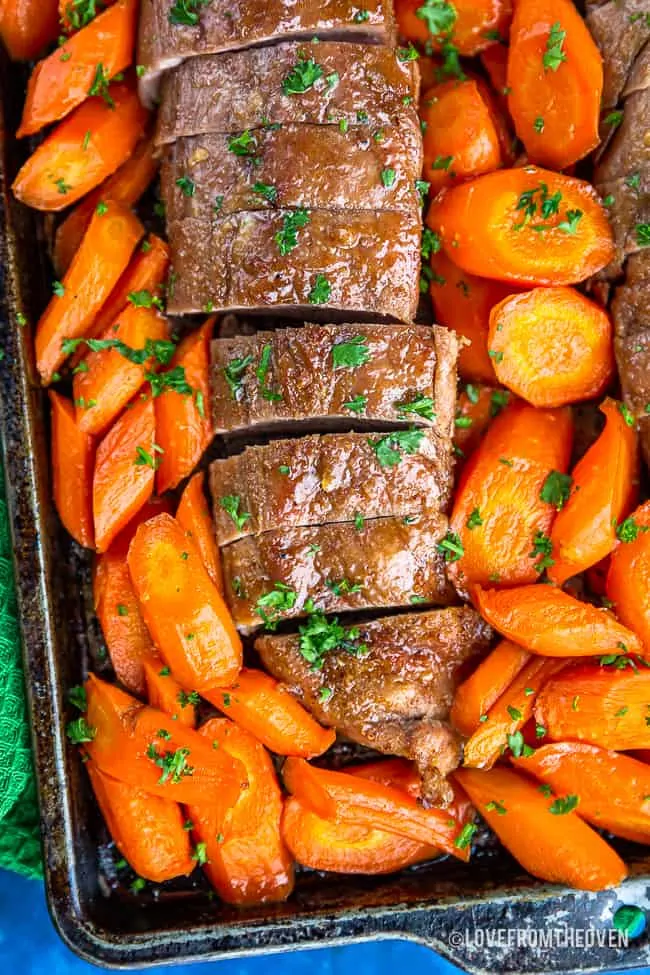 Close up of pork tenderloin surrounded by carrots