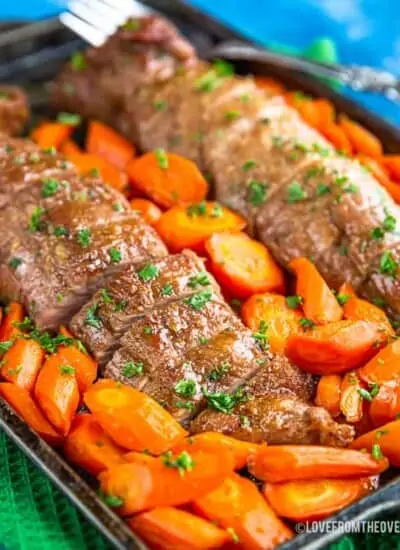 Pork tenderloin on a baking sheet surrounded by carrots