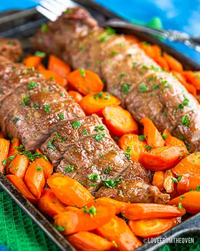 Pork tenderloin on a baking sheet surrounded by carrots