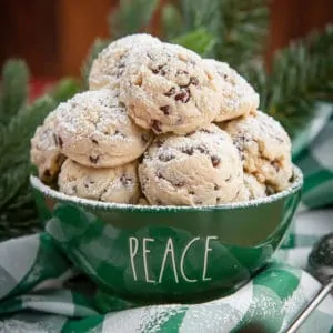 green bowl of chocolate chip snowball cookies with powdered sugar sprinkled on top