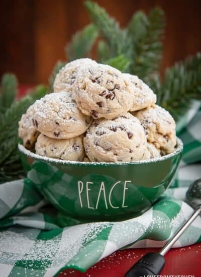 green bowl of chocolate chip snowball cookies with powdered sugar sprinkled on top