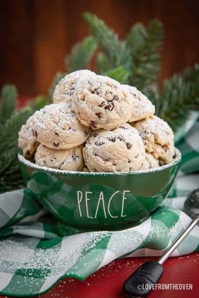 green bowl of chocolate chip snowball cookies with powdered sugar sprinkled on top