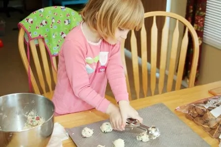 Little girl scooping out cookie dough onto a baking sheet