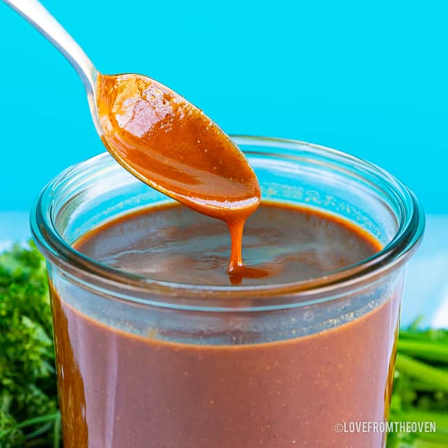 Spoonful of enchilada sauce dripping into jar