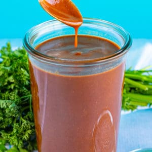 Jar of Easy Red Enchilada Sauce with a spoon dipping into sauce