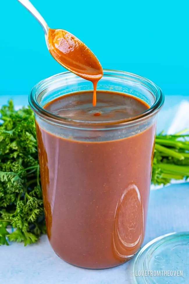 Glas einfache rote Enchilada-Sauce mit einem Löffel, der in Sauce eintaucht