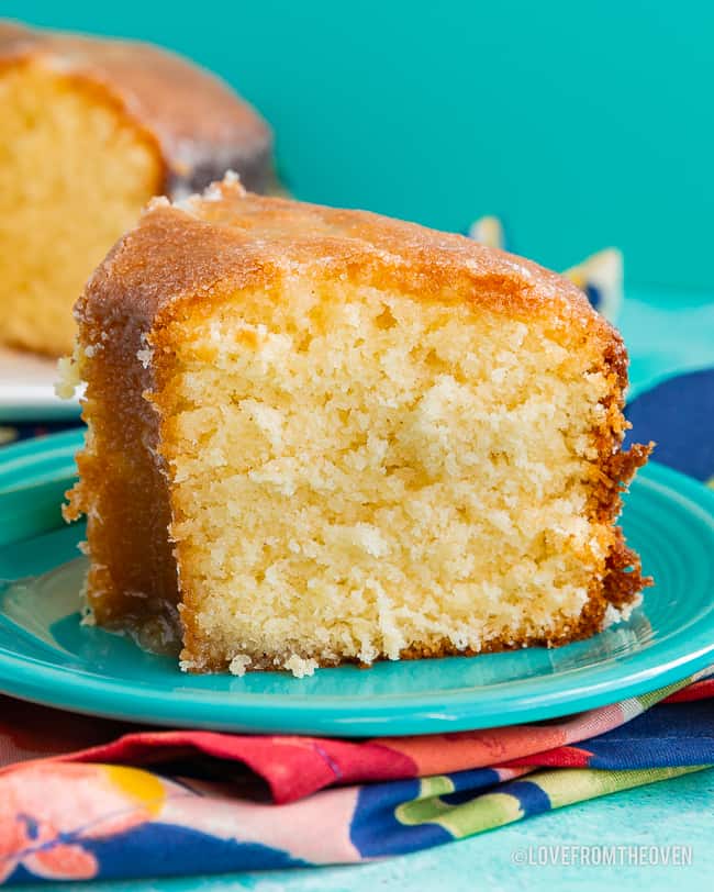 Slice of Kentucky Butter Cake on a blue plate, with a floral napkin, and the remaining cake sitting in the background. 