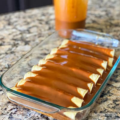 Enchiladas covered in enchilada sauce in glass baking pan