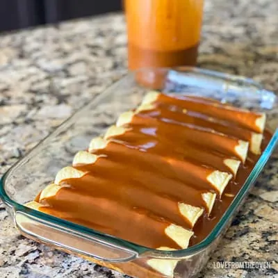 Enchiladas covered in enchilada sauce in glass baking pan