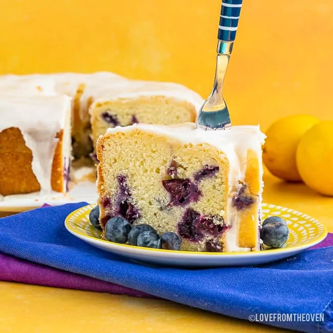 A piece of cake on a blue plate, with Lemon and Blueberry