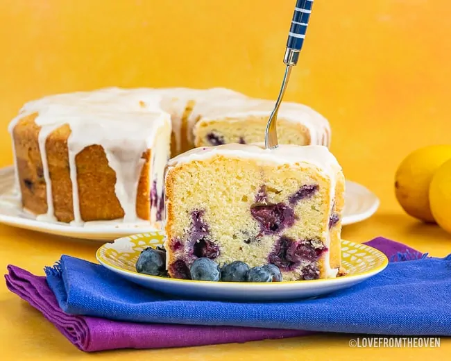 A slice of cake on a plate, with Lemon and Blueberry