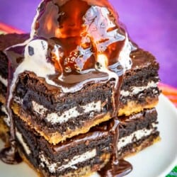 Brownies on a plate topped with ice cream and chocolate sauce