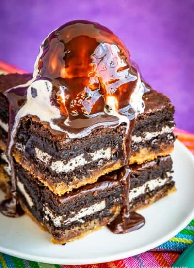 Brownies on a plate topped with ice cream and chocolate sauce