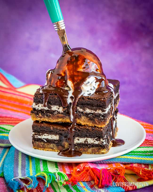 Two brownies on a plate topped with ice cream and chocolate sauce