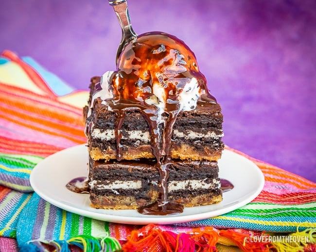 Brownies on a plate topped with ice cream and chocolate sauce