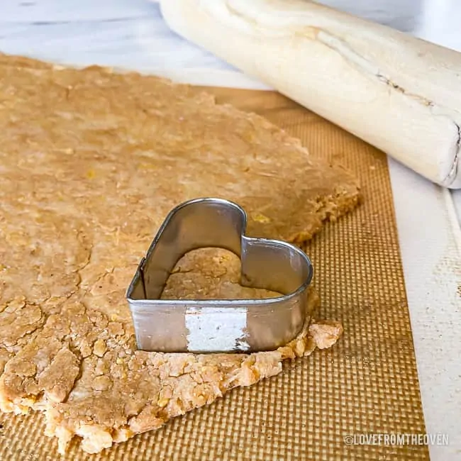 A heart cookie cutter on the dough to make peanut butter dog treats