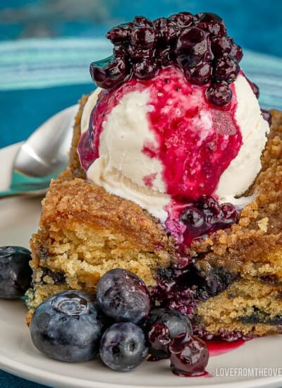 slice of blueberry buckle topped with ice cream and blueberry sauce