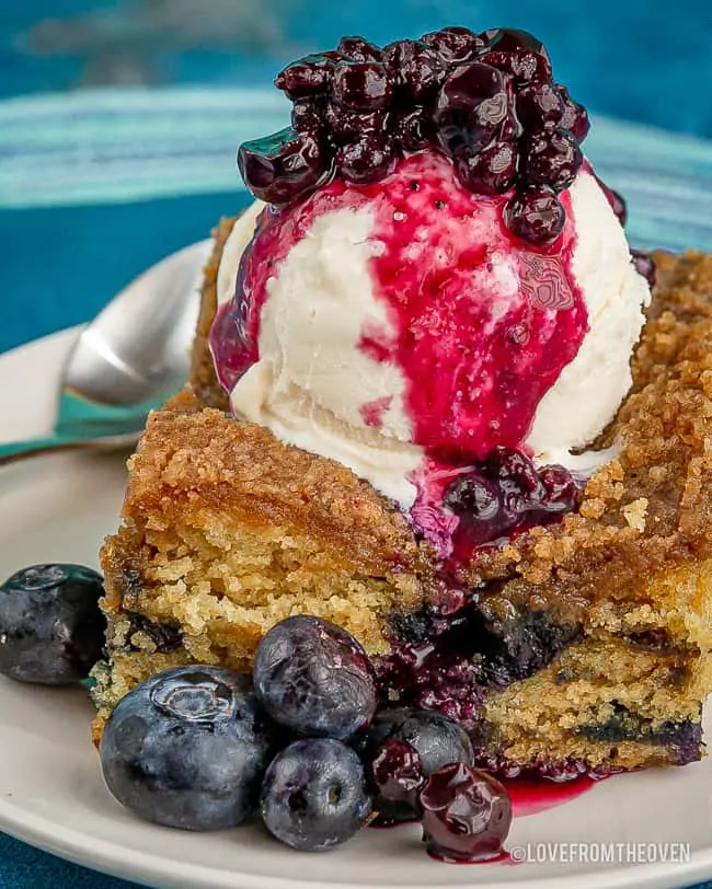 slice of blueberry buckle topped with ice cream and blueberry sauce