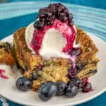 Slice of blueberry buckle topped with ice cream and blueberry sauce