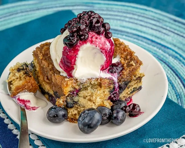 Slice of blueberry buckle cake topped with ice cream and blueberry compote