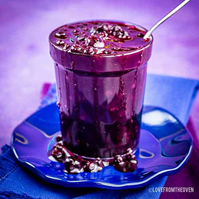 Jar of homemade blueberry compote on a blue plate