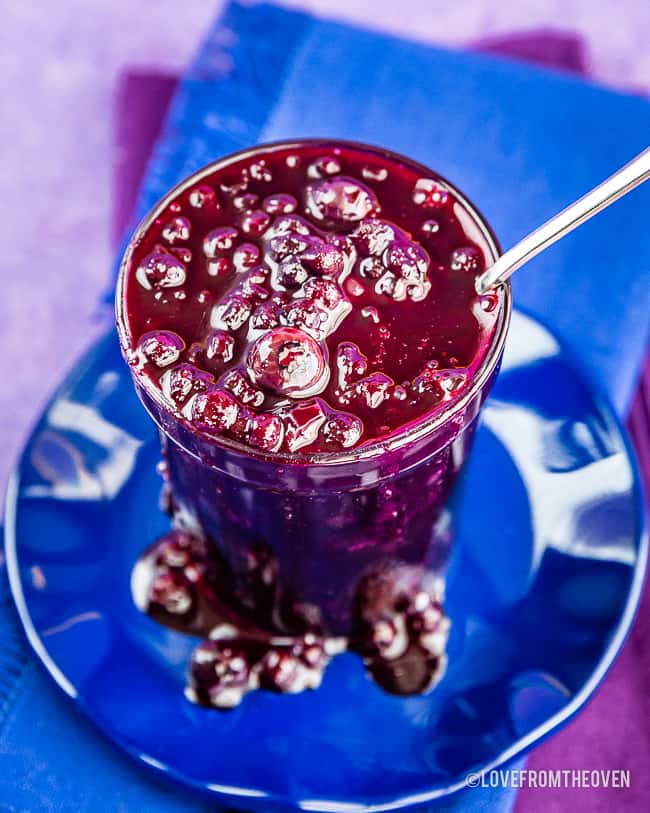 Glass jar of blueberry compote on a blue plate