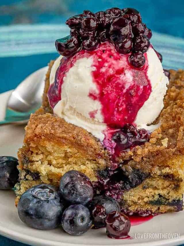 slice of blueberry buckle topped with ice cream and blueberry sauce
