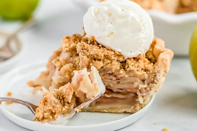 Slice of dutch apple pie with a scoop of vanilla ice cream on top