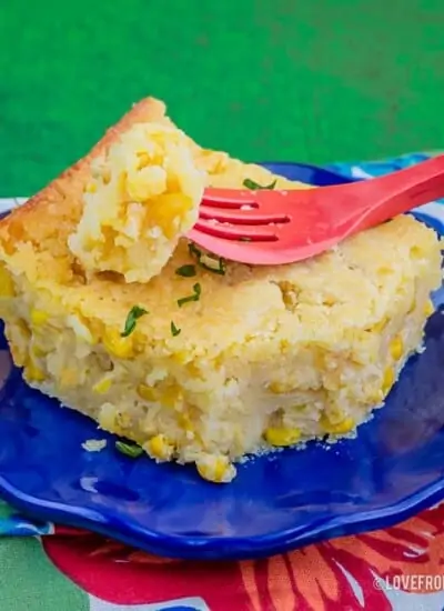 Slice of Jiffy Corn Casserole on a blue plate with a red fork